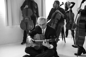 Gideon is sitting criss-cross applesauce on the ground at a photoshoot, holding his cello in his lap like one would a guitar. His left hand is barring a chord as if it's a guitar. Someone needs to tell Gideon it's not a guitar.